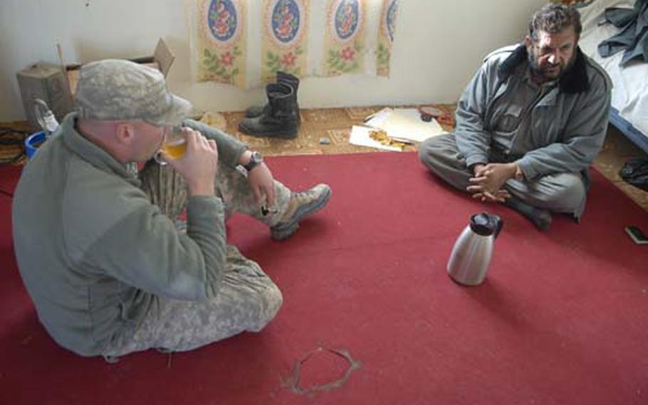 U.S. Army Staff Sgt. Jeff Schaffer drinks tea with an Afghan National Police station commander in Kandahar. Schaffer is part of a platoon moving into the substation as part of a program to train more closely with the Afghan security forces.