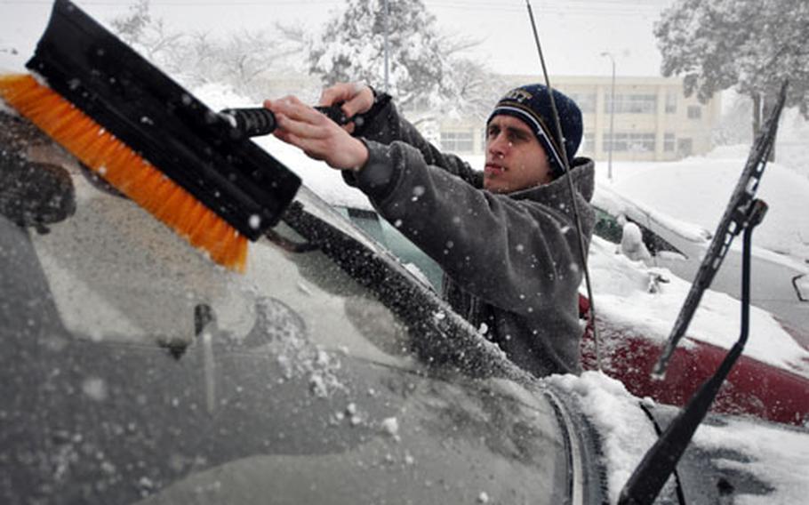 Air Force Staff Sgt. Tim Saar cleans snow of his windshield Wednesday morning at Misawa.