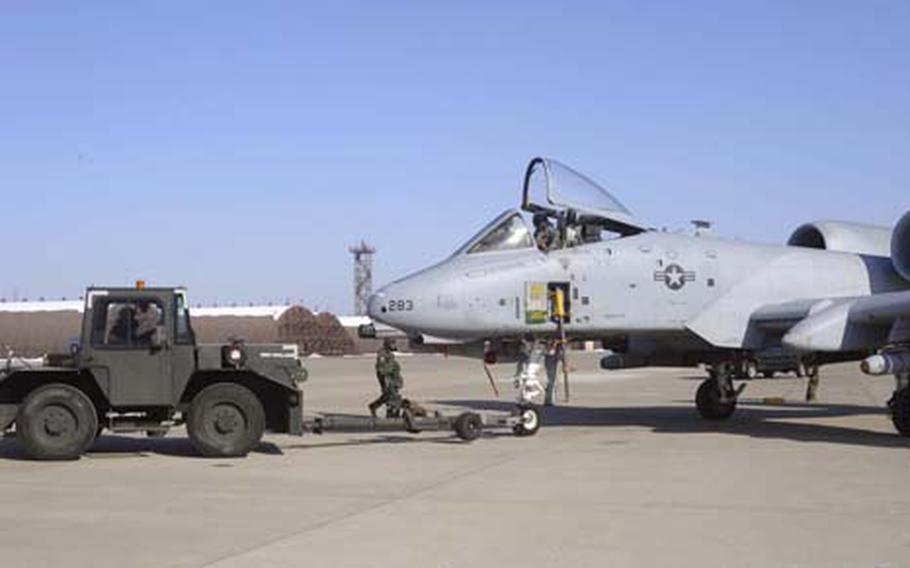 Airmen in chemical protective gear tow an A-10 Thunderbolt II attack plane of the 25th Fighter Squadron to a hangar for maintenance during a mock air war exercise. Some U.S. soldiers and South Korean air force units also took part.