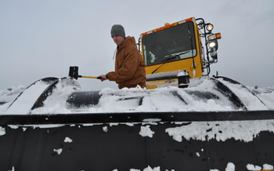 Staff Sgt. Matthew Fenton clears snow of the plow he was using to clear the air field on Wednesday morning following 14 inches of overnight snow at Misawa Air Base, Japan.
