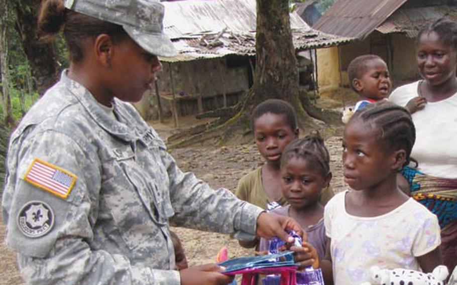 Sgt. 1st Class Dedraf Blash passes out school supplies to children in a Liberian village near Camp Sandi Ware, where she spent three months helping run a military medical clinic and mentoring female soldiers in the Armed Forces of Liberia.
