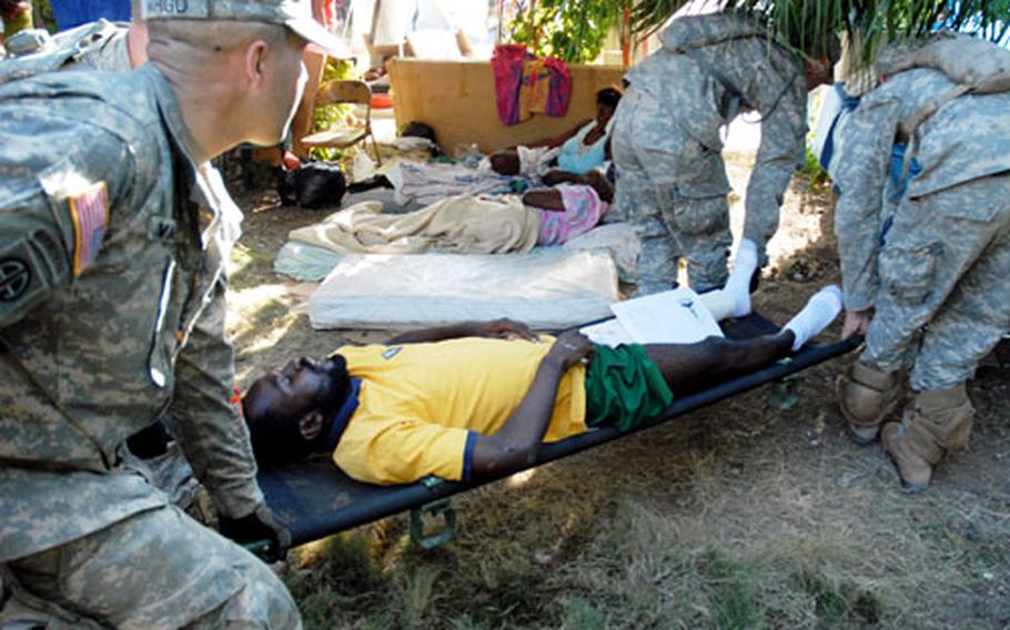 Soldiers carry an injured Haitian man from the main Port-au-Prince hospital to an Army ambulance, which was taking patients to the presidential palace for a helicopter transport to the USNS Comfort on Thursday.