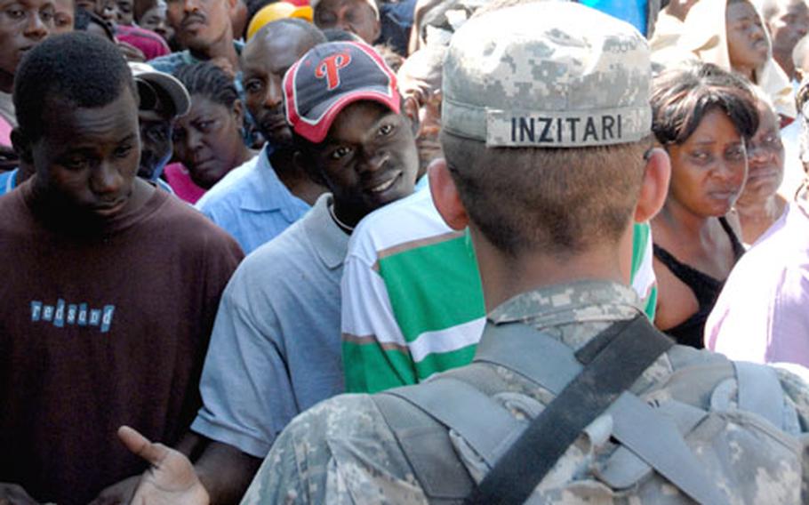 Pfc. Anthony Inzitari stands at the gate Friday talking to Haitians who were trying to get inside the main Port-au-Prince hospital.