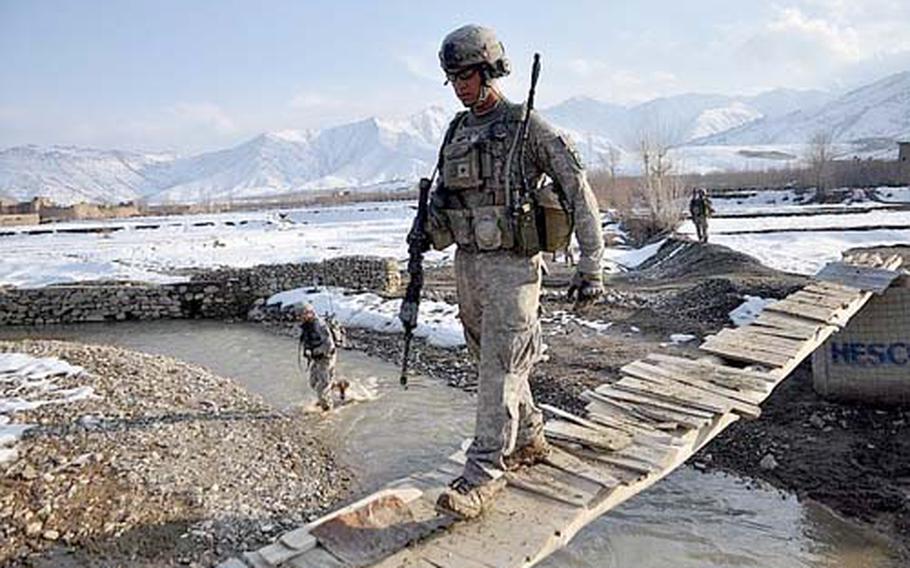 Spc. Nick Young, 23, of Venice, Fla., walks across a rickety bridge in Wardak province while a fellow soldier splashes through the river during a recent foot patrol near Kane Izat.