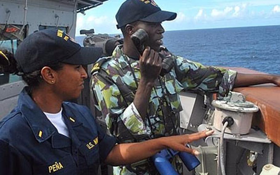 Ensign Emily Pena, left, an engineering officer aboard the guided-missile frigate USS Nicholas, instructs an Africa Partnership Station East student how to communicate ship coordinates with the bridge during a man-overboard drill.