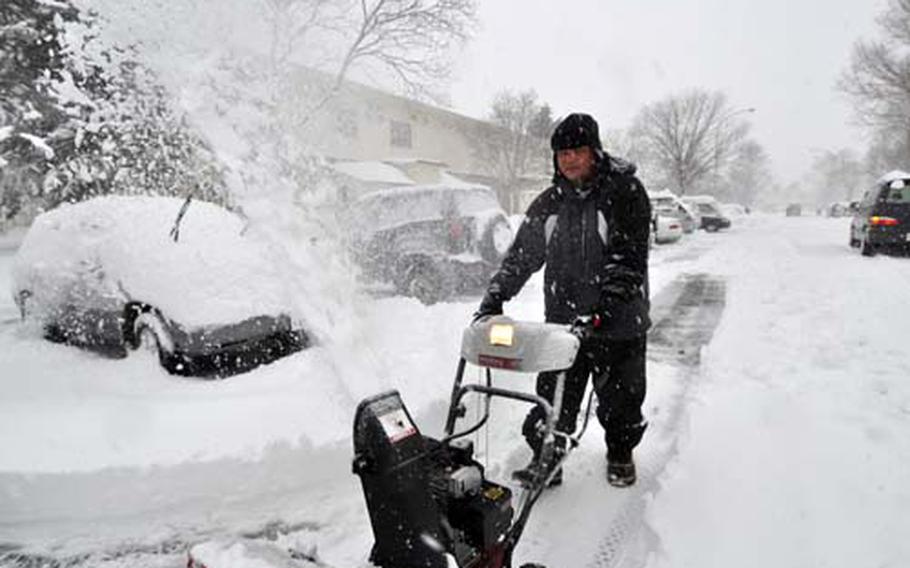 Air Force Master Sgt. Greg Pocaigue uses a snowblower to dig out his car.