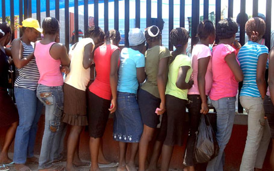 Haitian women wait in line at a food distribution point in the city of Carrefour on Wednesday.