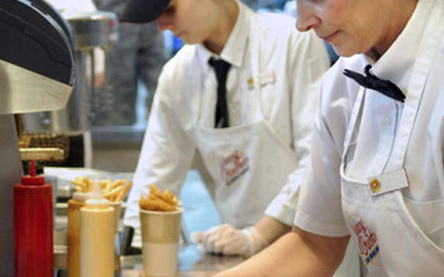 Kitchen staff of the Johnny Rockets fast food restaurant prepare food for patrons Tuesday at Ramstein&#39;s Kaiserslautern Military Community Center food court.