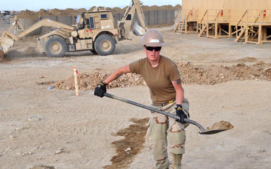 Constructionman McKenzie Dupons, 20, a Navy Seabee, carries dirt to fill in the frame for a concrete floor where she works at the construction site at Forward Operating Base Sharana.