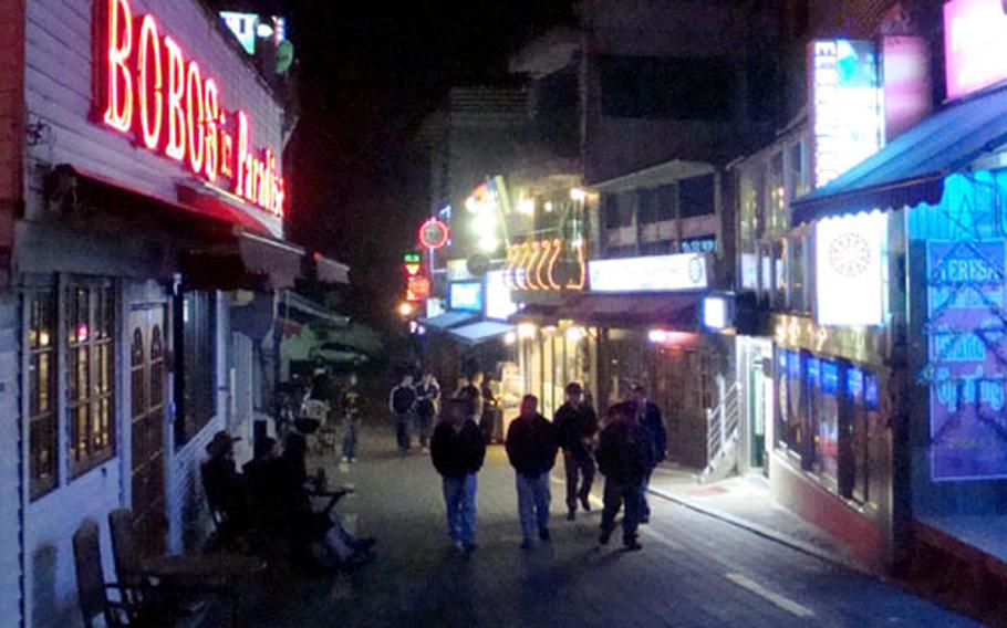 Servicemembers from Kunsan Air Base in South Korea walk down one of the streets in nearby America Town, which is home to a number of "juicy bars."