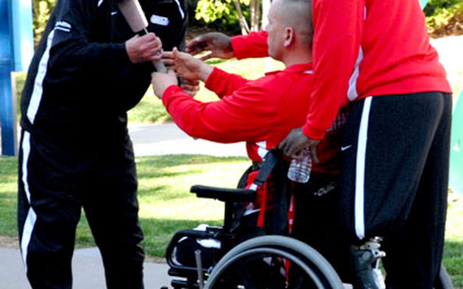 Army Sgt. Robert Price, who lost part of his right leg in Iraq, passes the torch to former Lance Cpl. Charles Sketch, who is a blind double-amputee, with the help of Gunnery Sgt. Marcus Wilson, during the opening ceremony Monday at the inaugural Warrior Games for wounded servicemembers. The torch was passed from service to service.