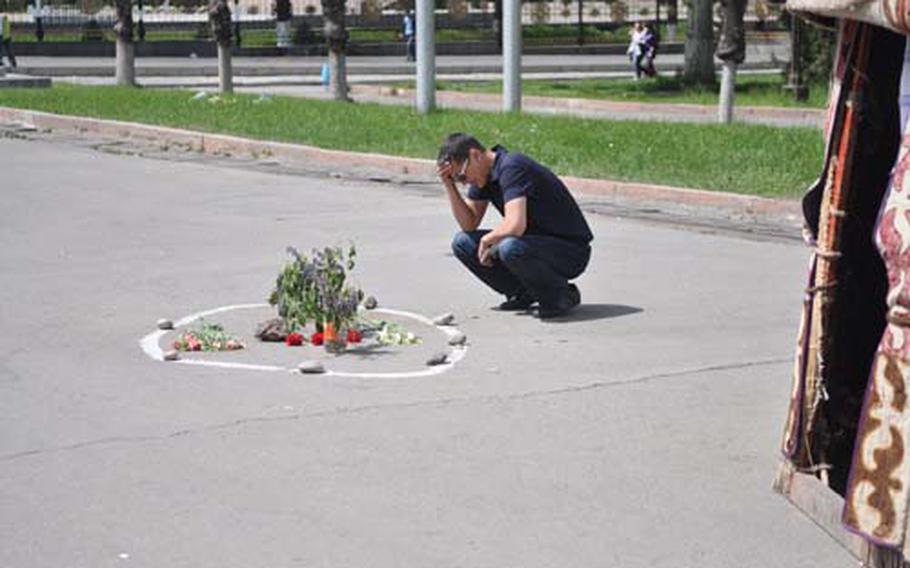 A man grieves at the site where a protester was killed during violent clashes in Bishkek between government forces and protesters. Flowers scattered around the city center mark the spot where each of the 84 protesters who were killed fell.