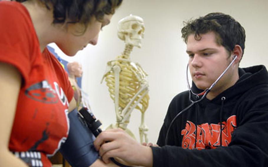 Nikolas Siegmund checks Kaitlin Hines&#39; blood pressure during health science class in January at Ramstein High School.