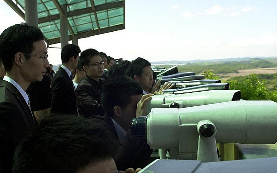 Visitors to the Dora Observatory at Korea&#39;s Demilitarized Zone use binoculars to look into North Korea on Wednesday. Tours to the DMZ continue apparently unaffected by rising tensions between North Korea and South Korea.