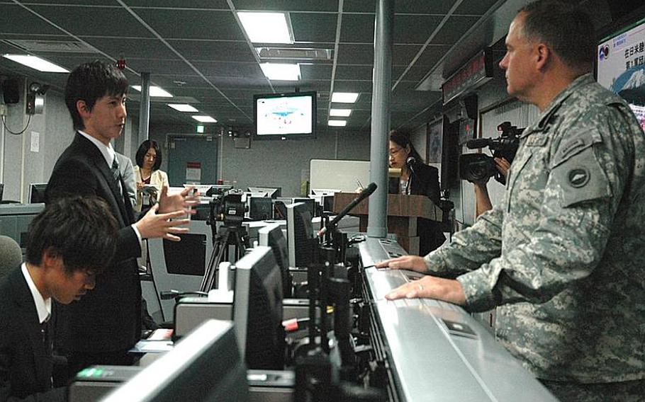 A Heisei International University student talks Friday with Maj. Gen. Francis Wiercinski, the U.S. Army?s commander in Japan, inside the Army&#39;s command and control room at Camp Zama. The students toured the base Friday as part of their thesis seminar about the U.S.-Japan alliance.