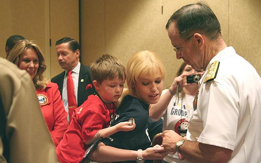 Adm. Mike Mullen, chairman of the Joint Chiefs of Staff, hands a coin to one of the roughly 375 children who lost a loved one in the military who attended "Good Grief Camp" Friday run by the Tragedy Assistance Program for Survivors.