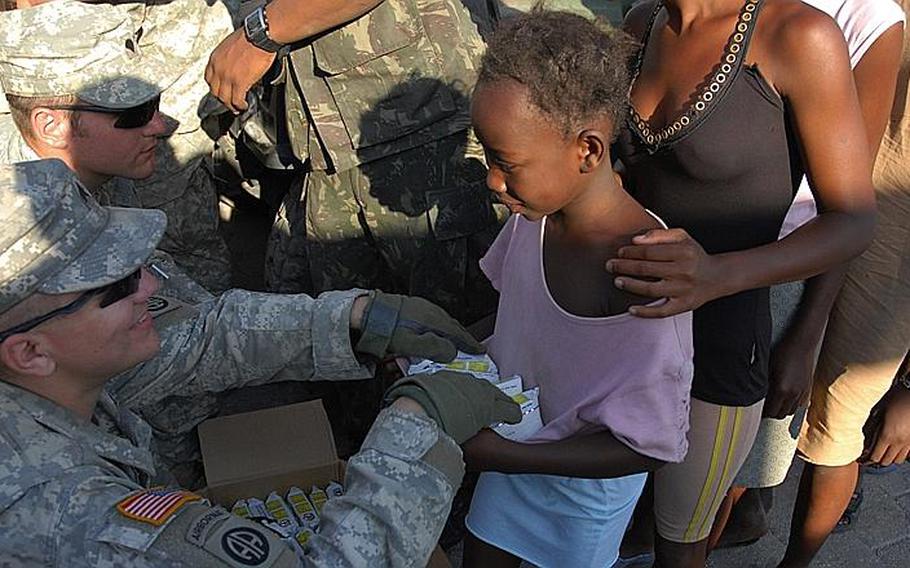 Sgt. Otis Richardson, Company A, 1st Battalion, 325th Airborne Infantry Regiment, hands out World Food Program high-calorie biscuits to children in City Soleil, one of Haiti&#39;s toughest neighborhoods. The Army is working in the area with a Brazilian contingent of UN soldiers.
