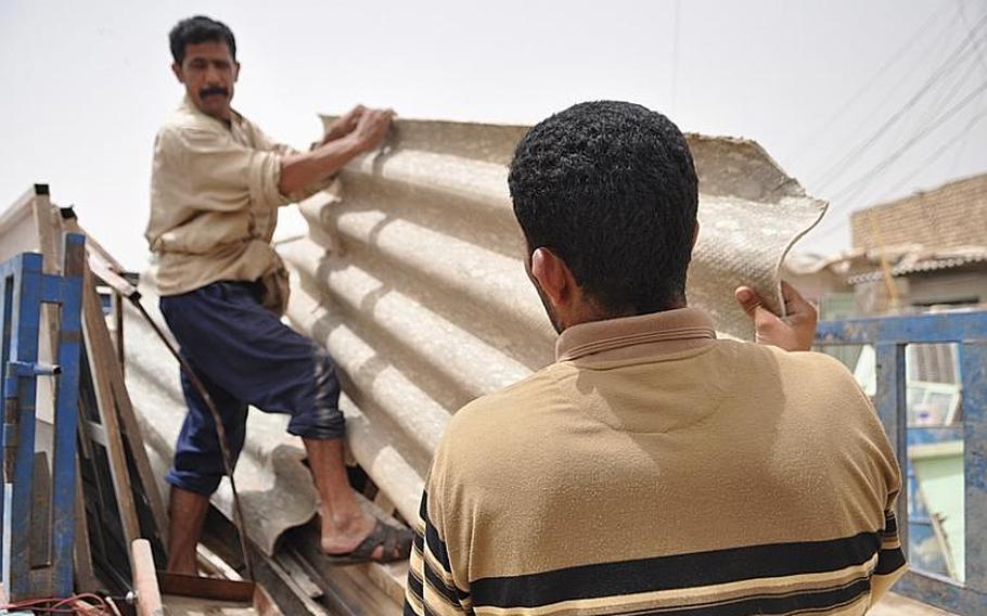 Residents of a squatters' camp load part of a makeshift roof onto a truck on Tuesday. The impoverished residents tried to salvage anything of value ahead of the Iraqi government's steps to raze the settlement.