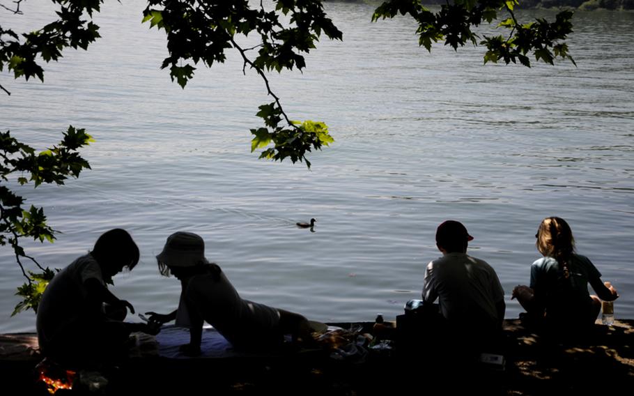 Children on the island of Mainau take a break from the sun to eat and feed the ducks that make Lake Constance their home this time of year. The lake is a clear emerald green and is at the bottom of the Rhine valley.