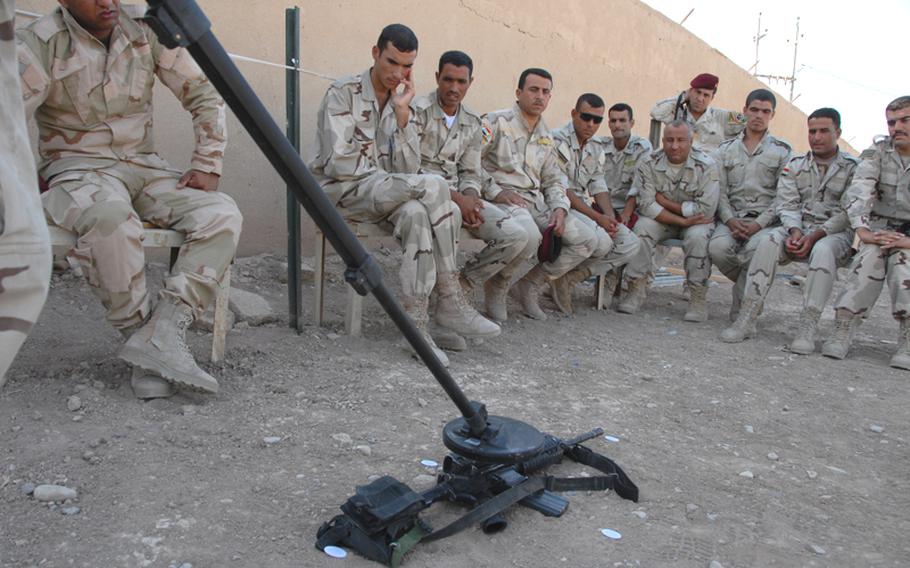 Soldiers with the 5th Iraqi Army Division in Diyala watch as one of their own shows how to use a metal detector to scan for hidden bombs and caches. The display was for the benefit of U.S. soldiers as well to judge the equipment and proficiency among the Iraqi soldiers before gearing up for long-term training sessions over the next few months.