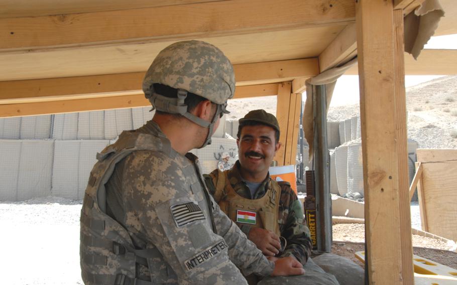 A U.S.-hired translators talks with a Kurdish Peshmerga soldier. The two Iraq groups speak different languages - Arabic and Kurdish - though sometimes Kurd soldiers know some Arabic. The U.S. soldiers also man the checkpoints, but they generally sit back from the road and watch as the Arab and Kurdish soldiers interact with the travelers.