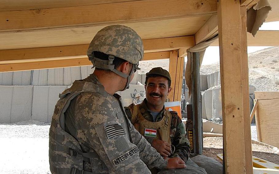 The U.S. soldiers also man the checkpoints, but they generally sit back from the road and watch as the Arab and Kurdish soldiers interact with the travelers. The two Iraq groups speak different languages, Arabic and Kurdish, though sometimes Kurd soldiers know some Arabic. Often, they rely on U.S.-hired translators, like the one here talking with a Peshmerga soldier, to communicate.