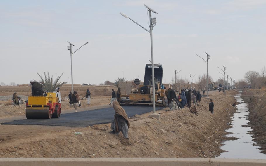 Workers and an audience gather at an unexpected event: the paving of street fronting central Marjah's bazaar. It is the first paved road in the town.