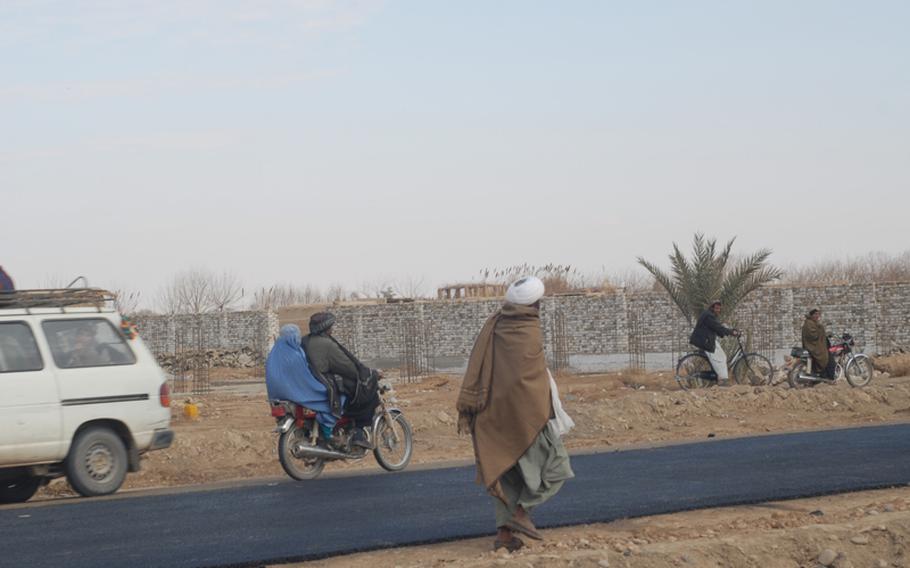 Women in Marjah are covered head to toe in burqas, and seen only in cars or on the backs of motorbikes, here traveling on the town's first paved road.