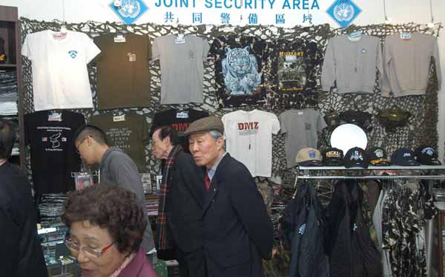 Tourists file Wednesday through the gift shop at the Joint Security Area Visitor Center at Korea&#39;s Demilitarized Zone. The most popular items sold there are T-shirts, a plaque featuring a piece of DMZ wire fence and liquor bottled at the Kaesong Industrial Complex in North Korea.