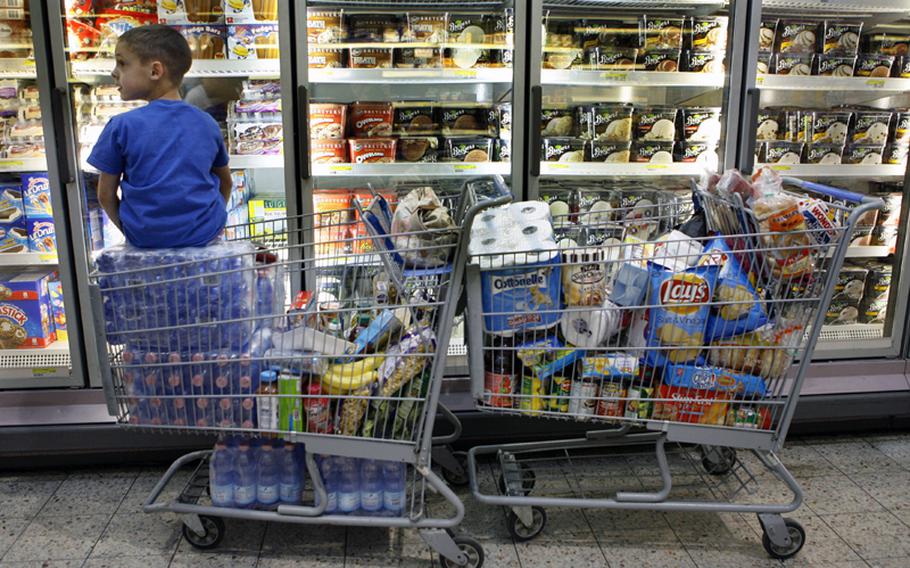 Carson Maxwell sits on the extra water and groceries his mother, Air Force Mst. Sgt. Cynthia Maxwell, was purchasing at Ramstein Air Force Base commissary in Germany on Friday, April 8, 2011. People were out in force on Friday stocking up in case the commissaries close due to the government shutdown.
