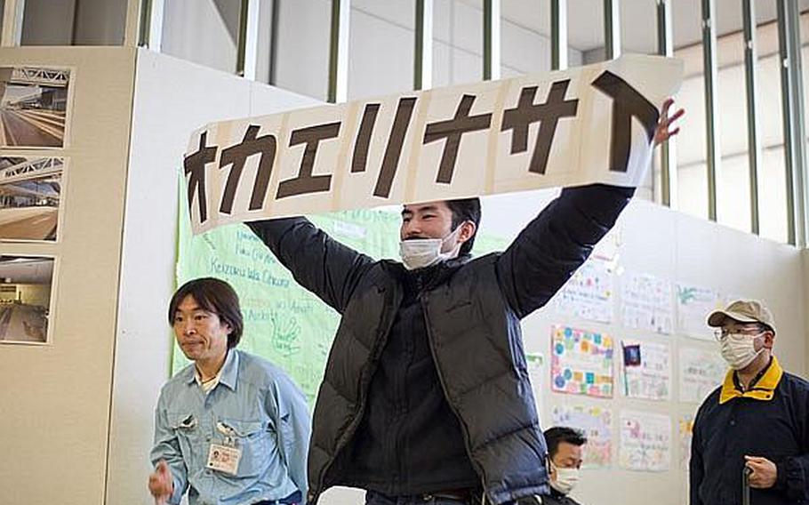 A man holds a &#39;welcome back&#39; sign in the terminal of Sendai Airport after a Japan Airlines Express flight from Haneda Airport landed - making it the first commercial flight to the airport since the March 11 tsunami ravaged the airport and region.