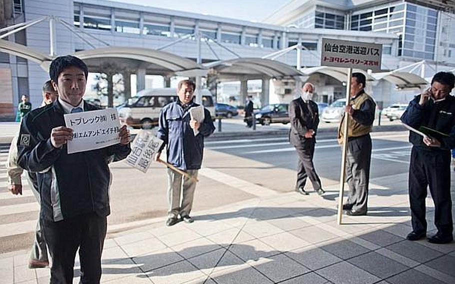 Transportation providers hold signs outside the terminal of Sendai Airport after a Japan Airlines Express flight from Haneda Airport landed - making it the first commercial flight to the airport since the March 11 tsunami ravaged the airport and region.