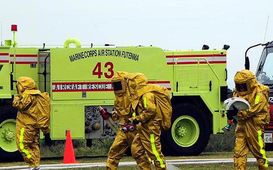 Firefighters grab hoses in preparation for dousing the flames on a simulated aircraft crash. The scenario was enacted as part of an annual bilateral training exercise between Japanese Emergency Response Teams and all branches of the U.S. military.