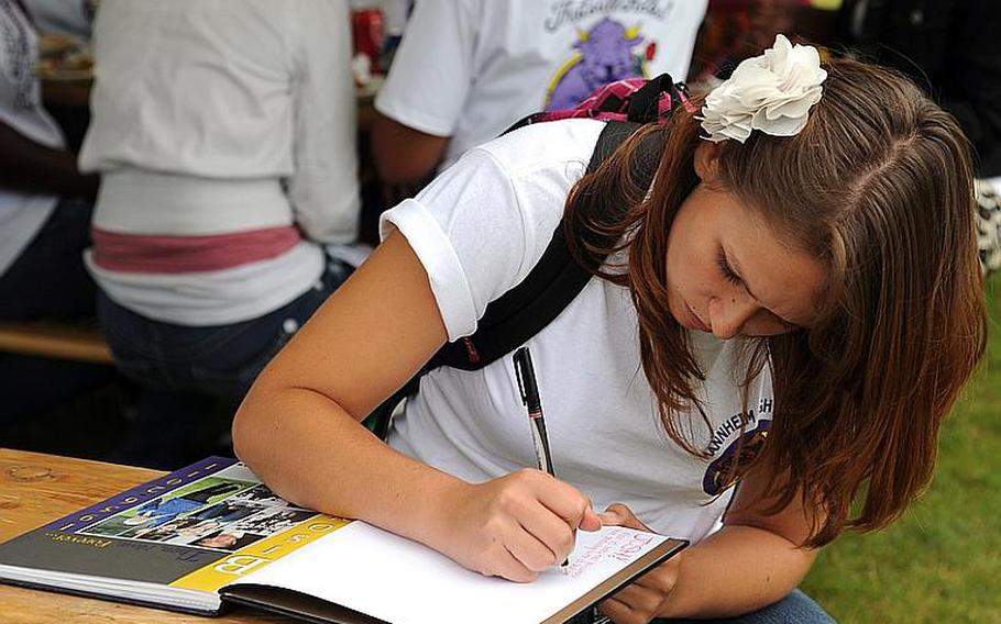 Mannheim High School senior Krystal Hartke writes in a schoolmate's yearbook following a closing ceremony for the high school and middle school on Thursday.