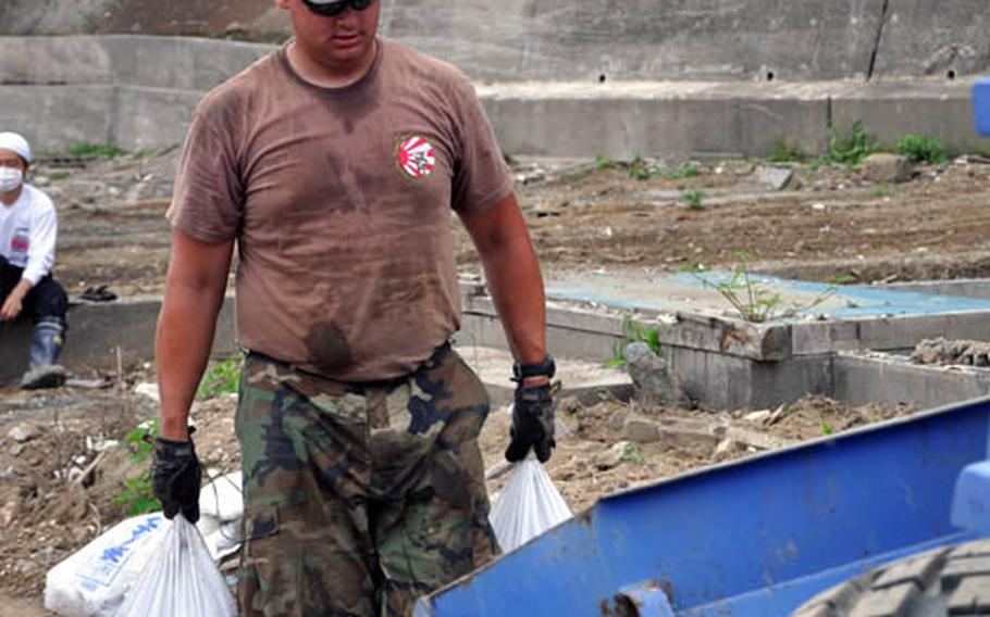 Petty Officer 1st Class Joshua Thonnissen lugs heavy bags of debris during clean-up efforts Thursday in Miyako, Japan.