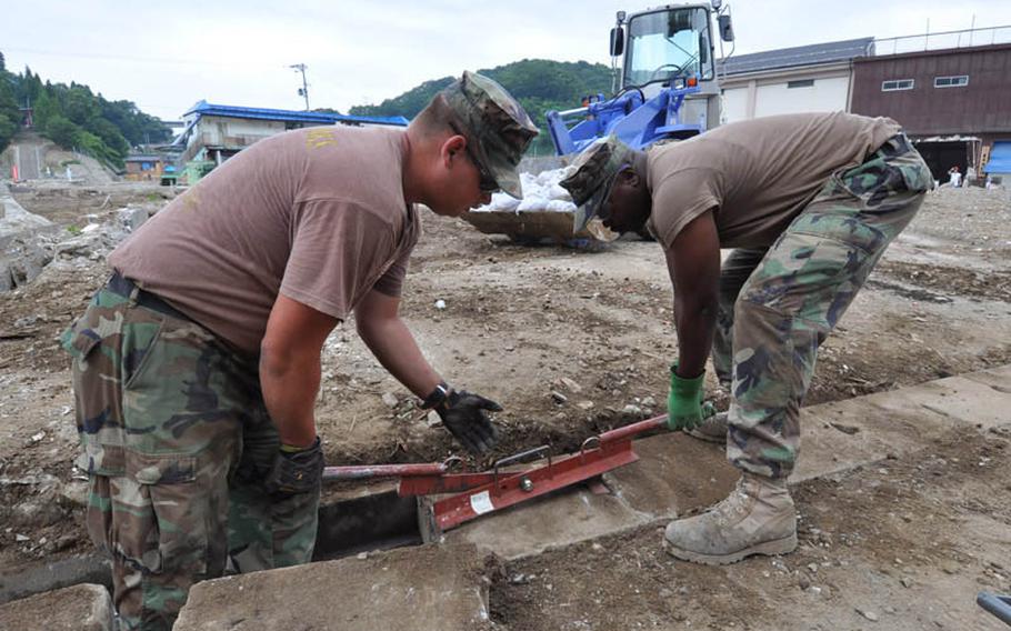 Petty Officer 1st Class Joshua Thonnissen, left, and Petty Officer 2nd Class Charles Hannah replace a heavy, brick drainage ditch cover while cleaning up tsunami damage Thursday in Miyako, Japan. The two Seabees, along with Chief Billy Knox, have spent nine weeks working in two Japanese communities.