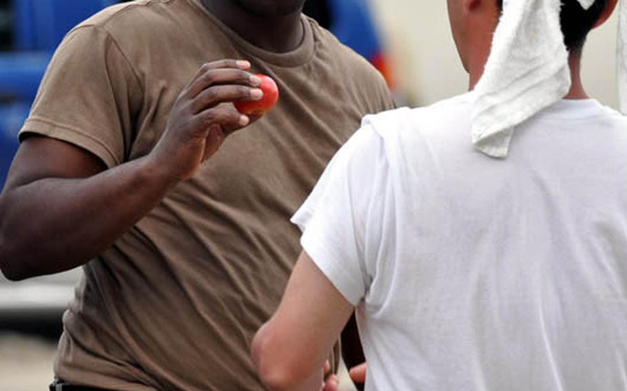 Petty Officer 2nd Class Charles Hannah accepts a tomato from a Japanese volunteer during a break Thursday while working in Miyako, Japan.
