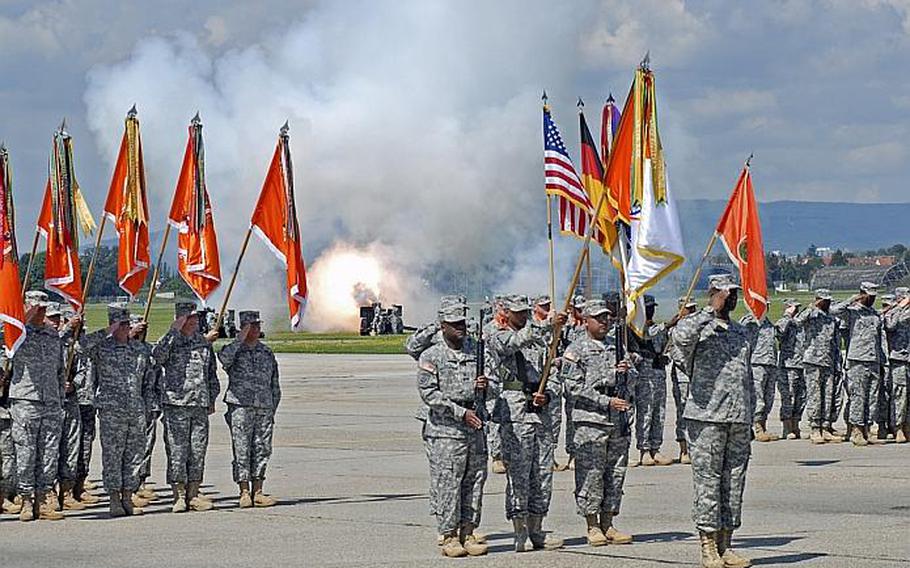 Soldiers from the 5th Signal Command perform salutes as cannons fire in the background.  Col. Bruce T. Crawford took the reins of 5th Signal Monday during a ceremony at Wiesbaden Army Airfield.