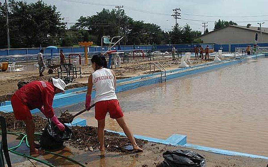 Staff and soldiers clear mud and debris around the  Hanson Fieldhouse pool at Camp Casey in South Korea.