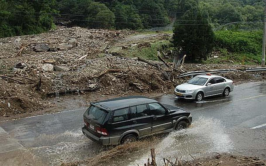 Vehicles drive Friday through an area of Camp Casey, South Korea, that was closed to traffic the day before because of mud and debris left by a landslide on the base. Heavy rains this week caused several landslides on the base, and caused extensive damage at two other bases north of Seoul.