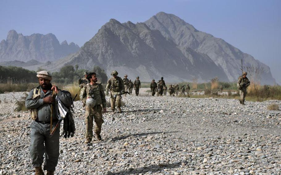 Afghan policemen and American soldiers walk along the banks of the Arghandab River after a night raid.