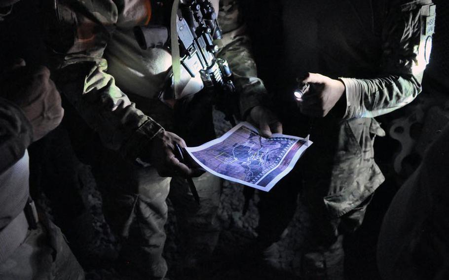 Soldiers of 3rd Platoon, Destroyer Company, 2nd Battalion of the 87th Infantry Regiment, review a map with a law enforcement contractor before a night air assault in southern Kandahar province. Contractors called law enforcement professionals, or LEPs, often accompany U.S. troops on raids to question and assist with processing of detainees. Many are employed by the company L3 MPRI.