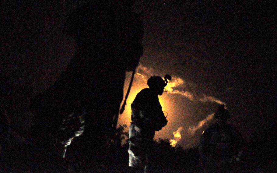 Soldiers of the 3rd Platoon, Destroyer Company, 2 Battalion of the 87th Infantry Regiment, are silhouetted by an illumination flare during a raid in southern Kandahar.