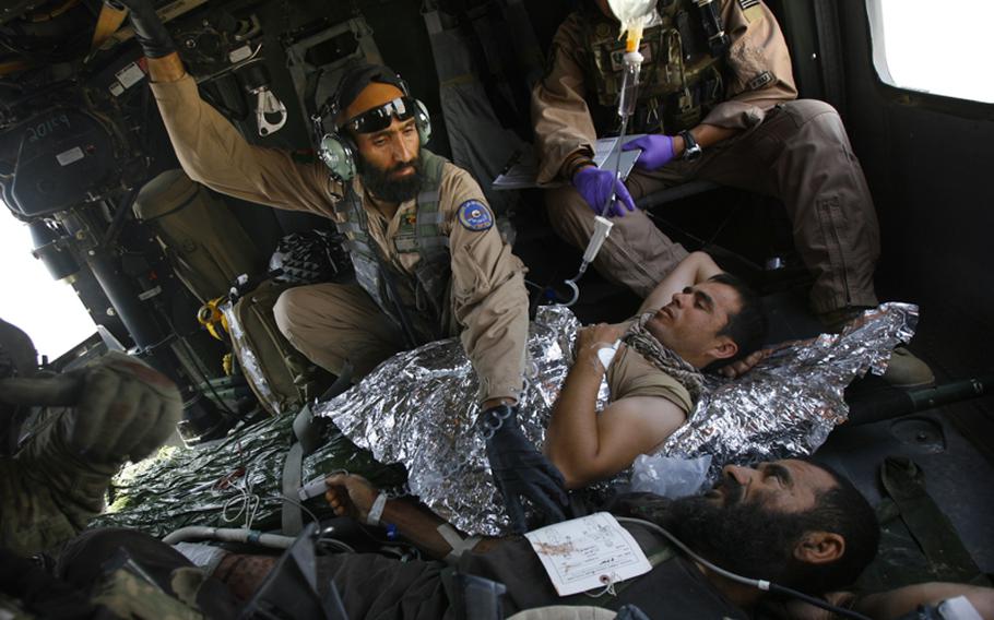 Afghan air force flight medic Sgt. Gulap Ahmadzia treats Afghan patients during a medevac mission June 29 near Kandahar Airfield. Soldiers with Company C, 1st Battalion, 52nd Aviation Regiment are training and mentoring the Afghans.