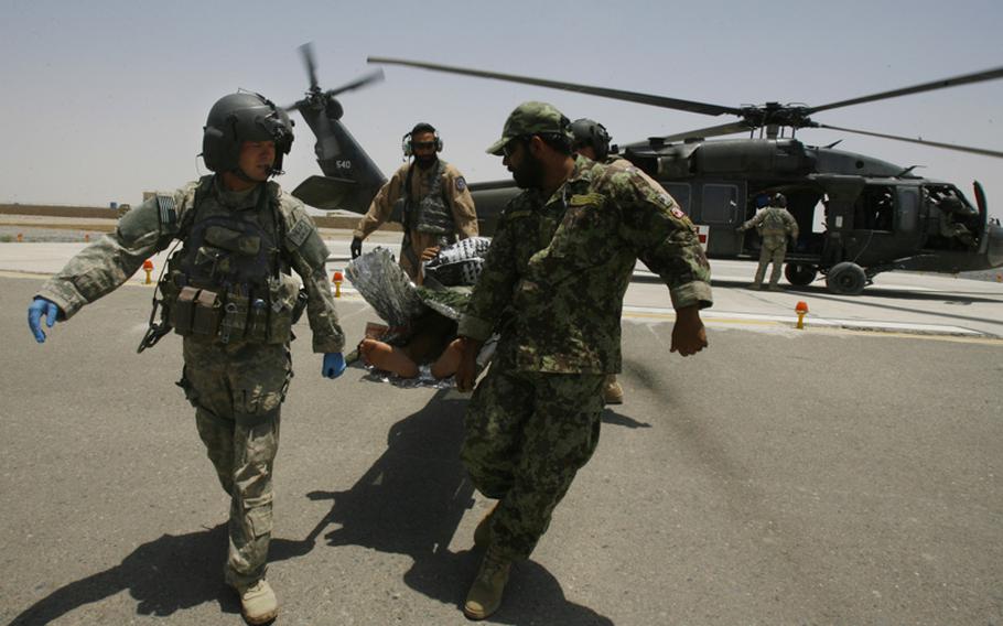 Staff Sgt. Kyle Clark, left, and Afghan air force Sgt. Gulap Ahmadzia, center back, along with hospital workers carry an Afghan patient to an ambulance at Camp Hero on June 29 at Kandahar Airfield. Soldiers with Company C, 1st Battalion, 52nd Aviation Regiment are training and mentoring the Afghan medics.