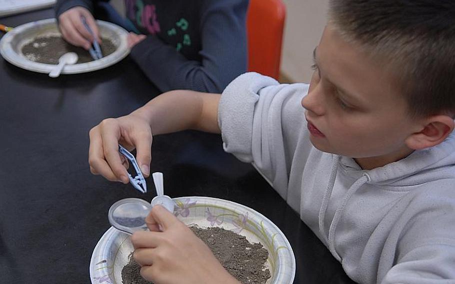 Xavier Buchholz, 12, examines a piece of sediment in teacher Tom Oliver's science class at Bitburg Middle School. Oliver's fifth and sixth graders are participating in the Mastodon Matrix Project, helping researchers in the states examine dirt unearthed from a mastodon evacuation site in New York. The project is part of an effort by Defense Department schools to encourage student interest and learning in science and math.