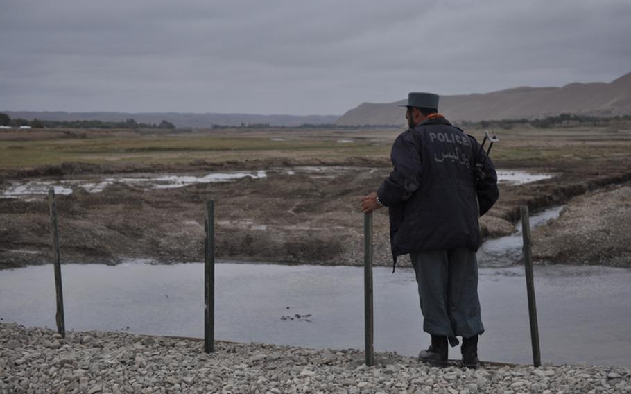 An Afghan National Police officer peers over the edge of a new bridge near the village of Gormach in western Faryab province.