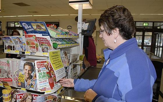 Air Force spouse Valerie Sheaffer reads a notice in the Vogelweh commissary on Tuesday informing customers that, after January of next year, all commissaries overseas will no longer sell magazines and most newspapers. Commissary officials say the move is an effort to save money in the face of dwindling magazine sales.

