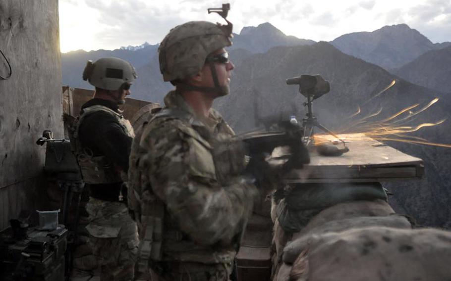 Sgt. Stephen McElroy with the 2nd Battalion, 27th Infantry Regiment fires a warning shot toward a valley route sometimes traveled by insurgents near Observation Point Mace in northern Kunar province as Senior Airman Joe McMullan looks on.