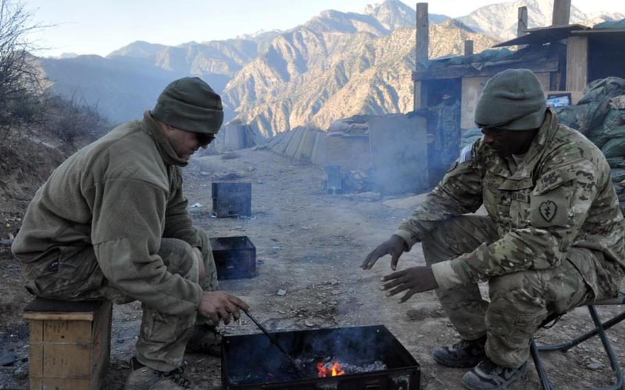 Spc. Anthony Corrado, left, and Sgt. Damien Chandler try to warm up on a cold morning at Observation Point Mace, which sits at an elevation of almost 6,000 feet in the Hindu Kush mountains of Kunar province.